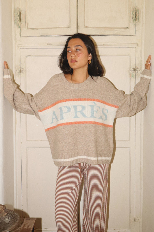 Woman wearing a sweater with 'APRES' text in a casual setting