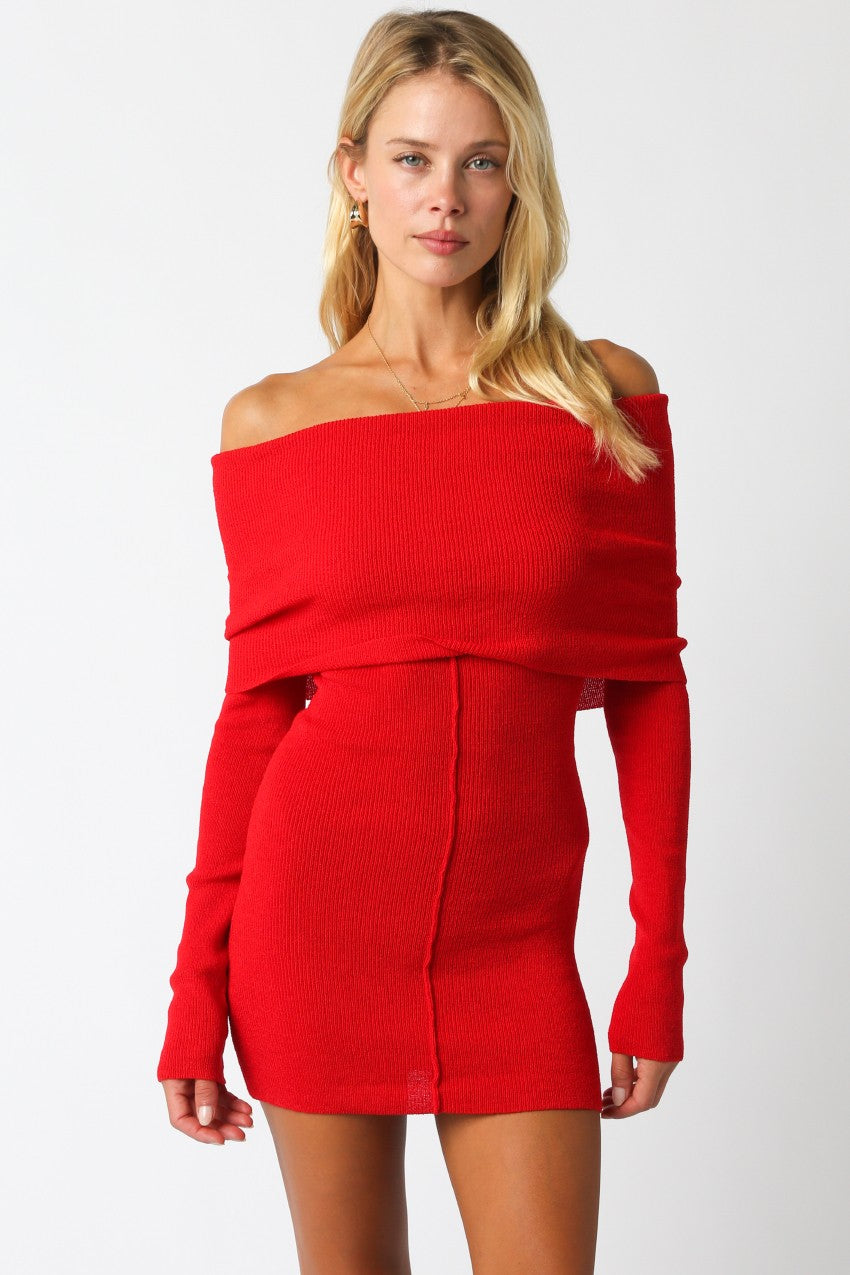 Woman wearing a red off-the-shoulder knit mini dress with long sleeves and a fitted silhouette.