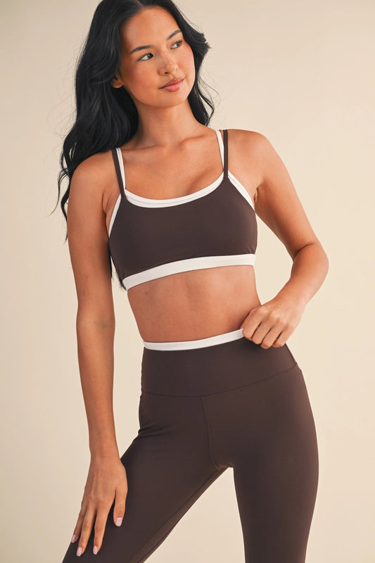 Woman wearing a brown sports bra and leggings set on a beige background