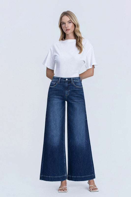 Woman wearing a white t-shirt and blue wide-leg jeans on a light gray background