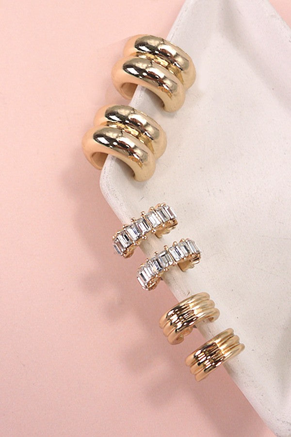 Set of gold and rose gold rings with clear gemstones on a pink background