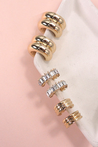 Set of gold and rose gold rings with clear gemstones on a pink background