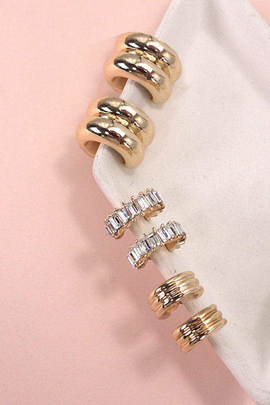Set of gold and rose gold rings with clear gemstones on a pink background