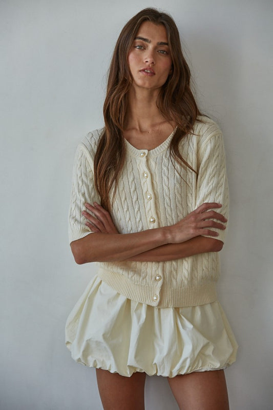 Woman wearing ivory bubble hem mini skort with slouchy socks and black ballet flats