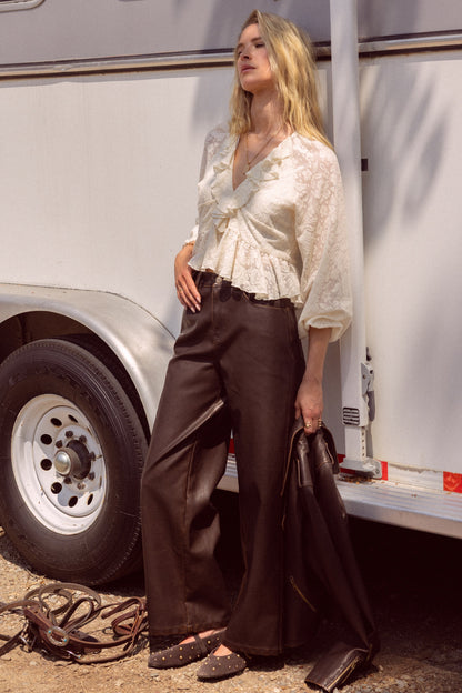 Woman in a white blouse and brown pants standing next to a white trailer.