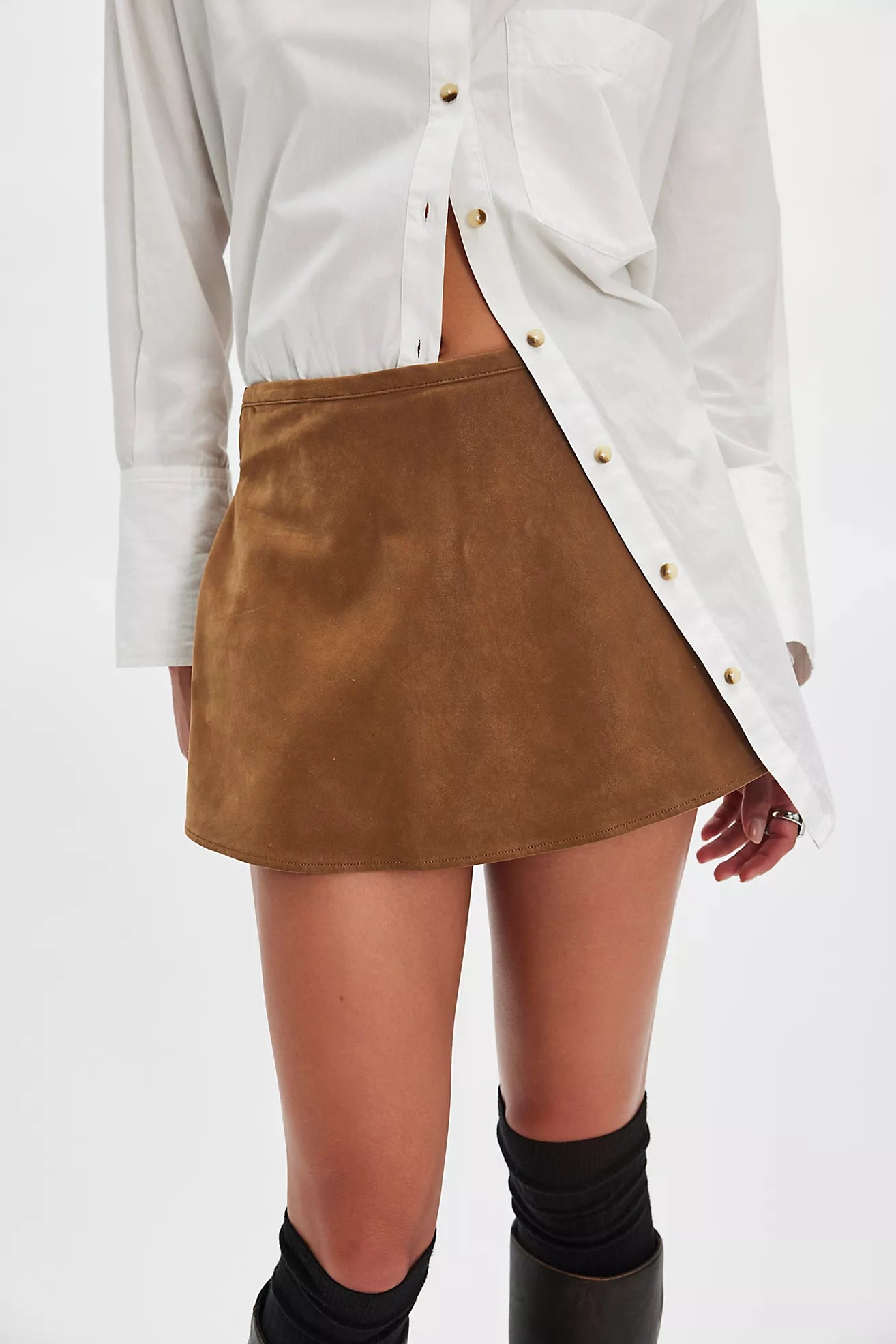 Model wearing camel suede skort with white button down.