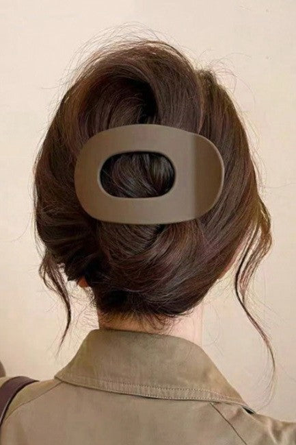 Person with a hair clip in their bun against a plain background