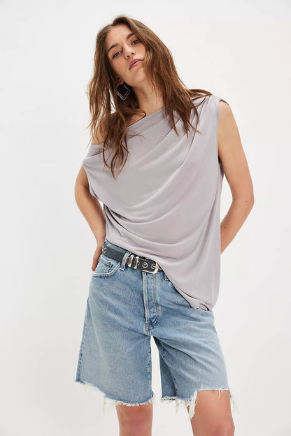Woman wearing a gray sleeveless top and denim shorts on a white background