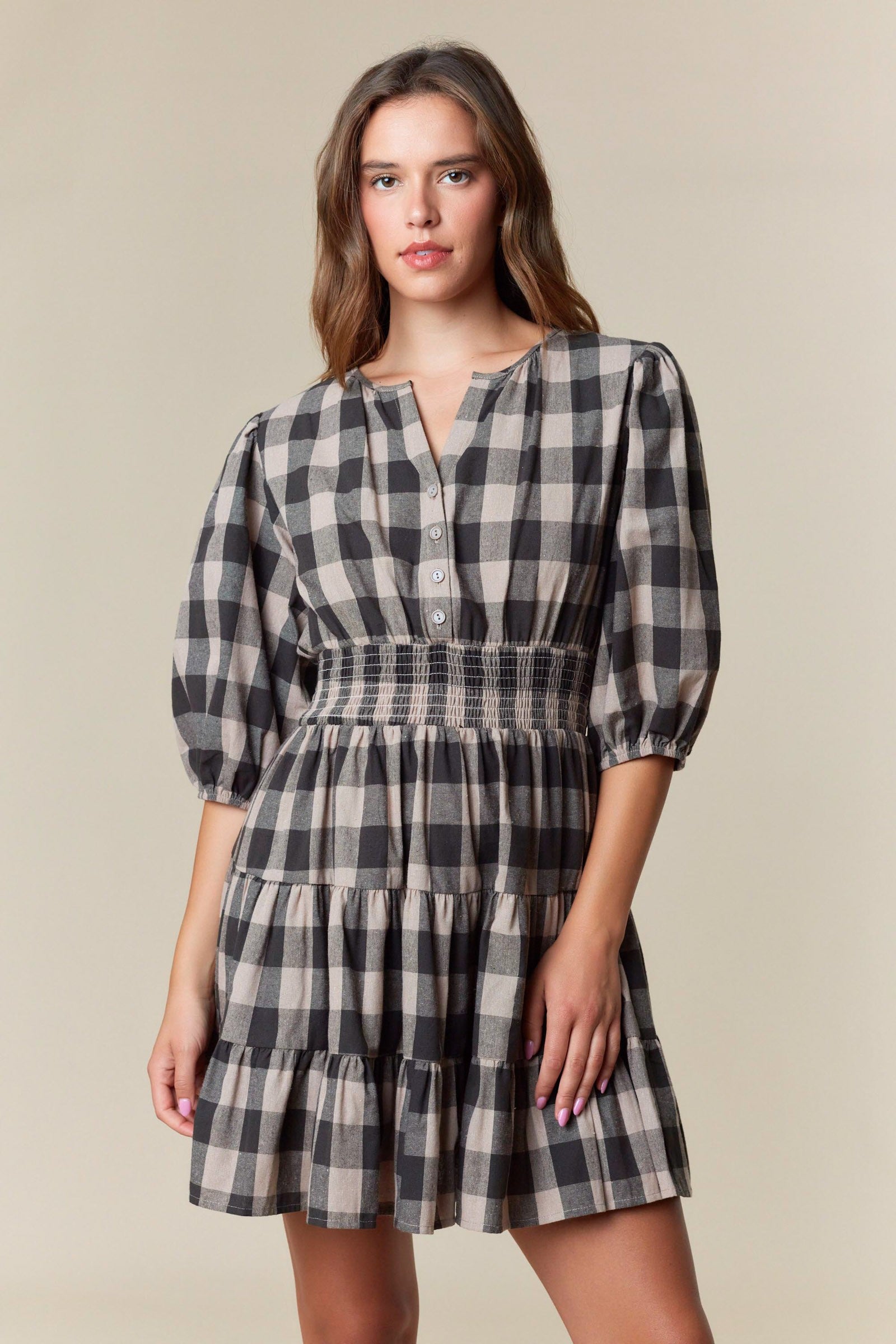 Woman wearing black and taupe plaid mini dress with smocked waist and puff sleeves