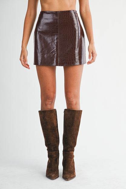 Model wearing high-waist crocodile-embossed faux leather mini skirt paired with tall suede boots.