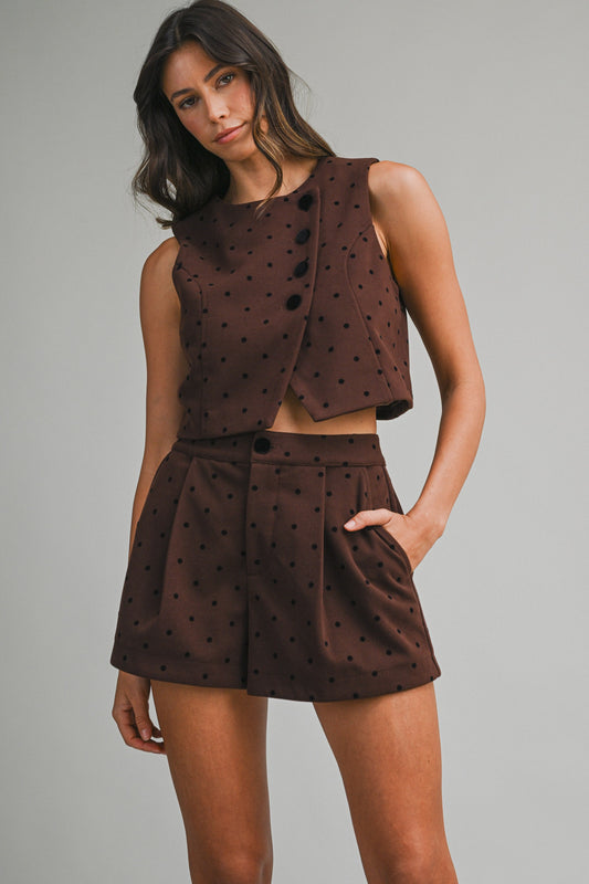 Woman wearing a brown polka dot outfit against a gray background