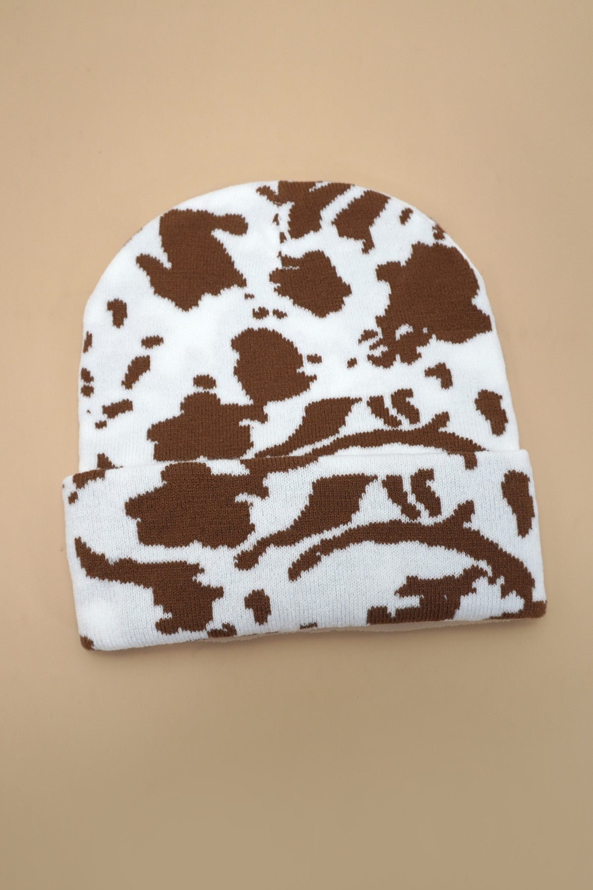 White beanie with brown abstract pattern on a beige background