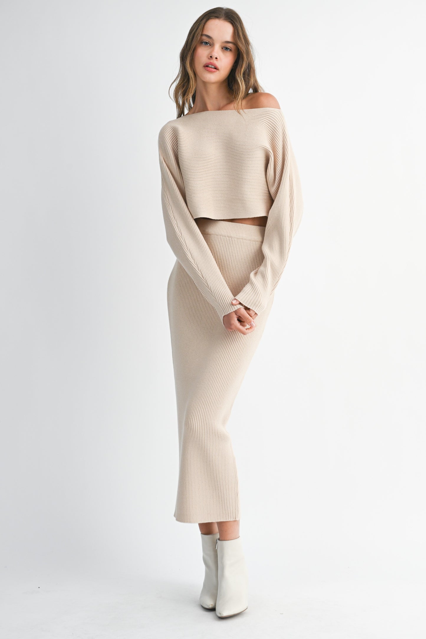 Model wearing beige ribbed knit co-ord set with long sleeve cropped sweater and matching bodycon midi skirt.