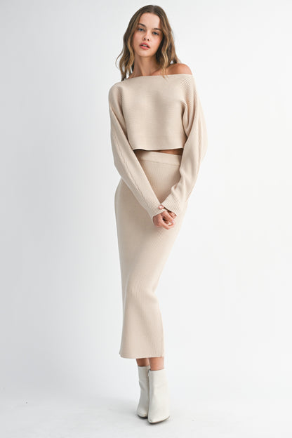 Model wearing beige ribbed knit co-ord set with long sleeve cropped sweater and matching bodycon midi skirt.