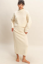 Load image into Gallery viewer, Model wearing ivory textured knit sweater and matching midi skirt set with high neckline and relaxed fit.