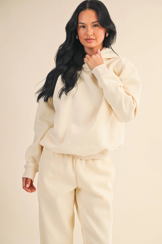 Woman wearing oversized cream fleece hoodie with relaxed fit and soft drape.