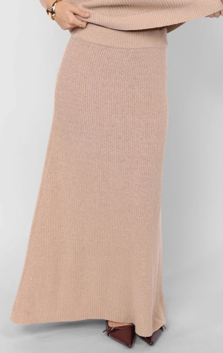 Model wearing cream ribbed knit midi skirt paired with matching turtleneck vest