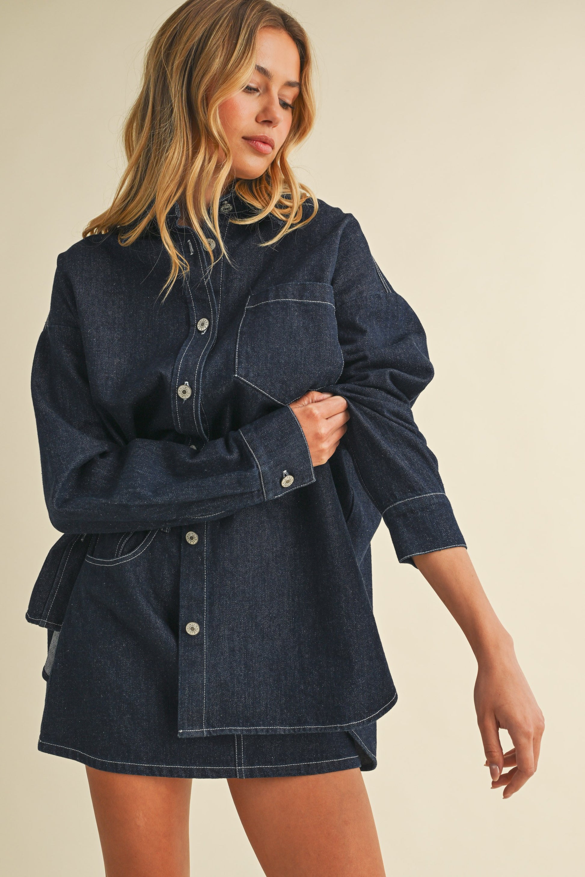 Model wearing dark-wash oversized denim shacket with matching mini skirt