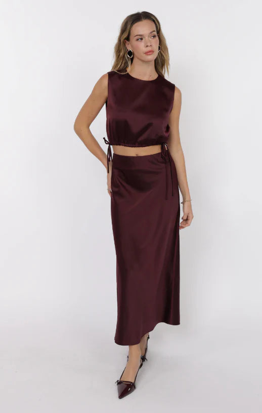 Model wearing wine satin sleeveless crop top with adjustable side ties