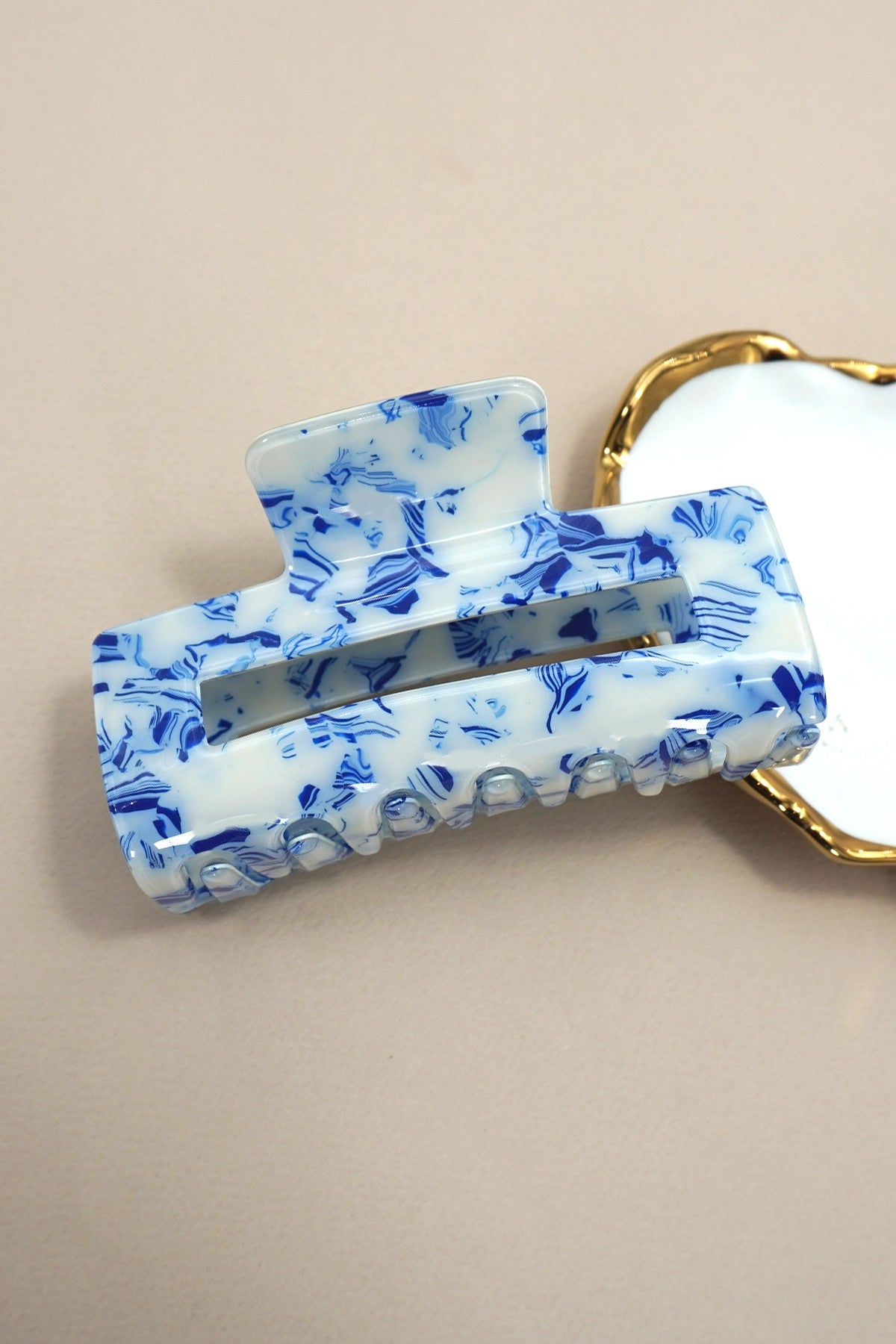Blue and white floral patterned hair clip on a beige background