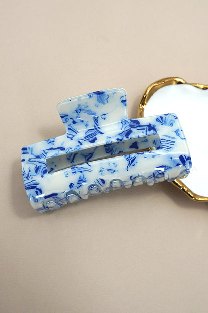 Blue and white floral patterned hair clip on a beige background