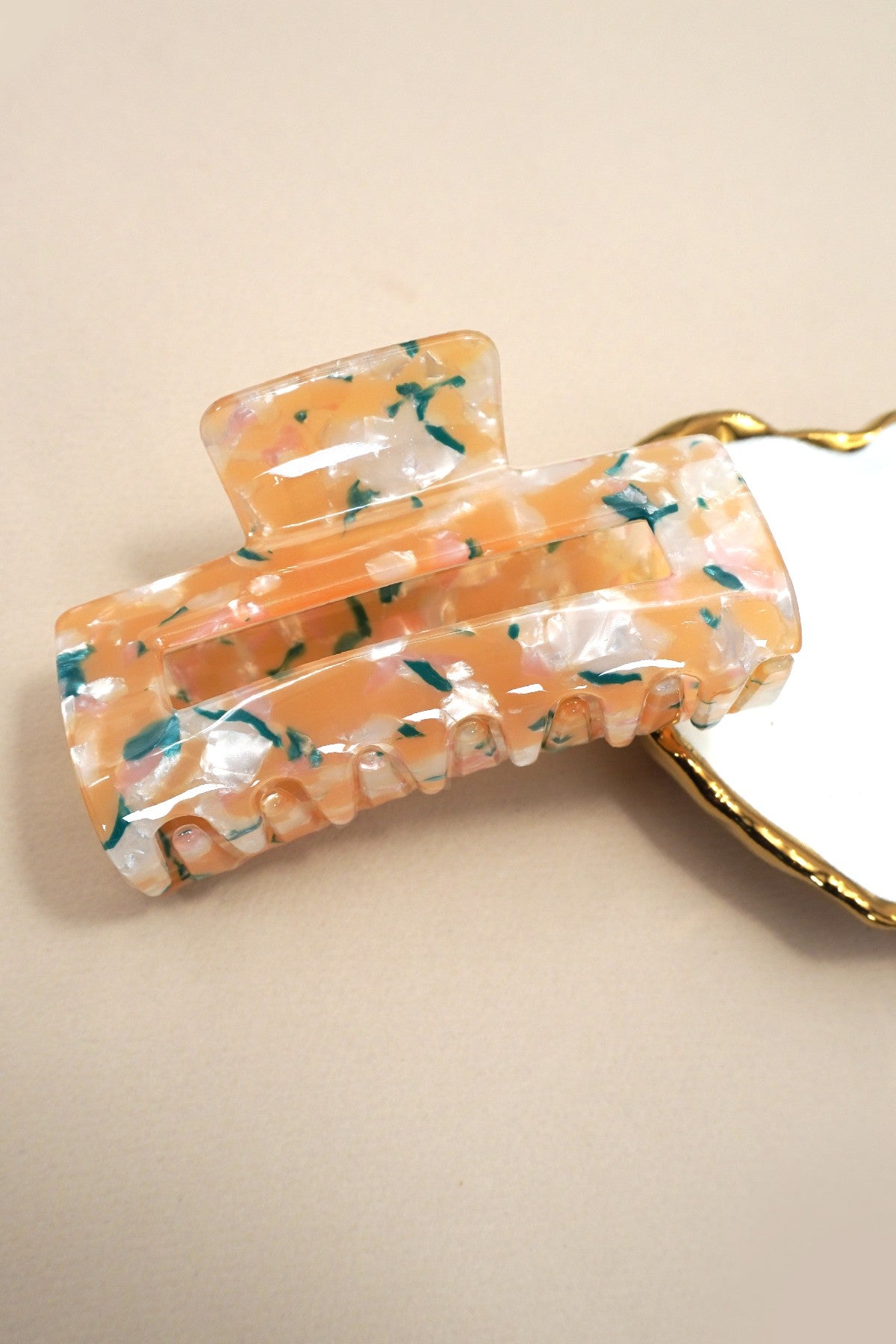 Decorative hair clip with floral pattern on a beige background