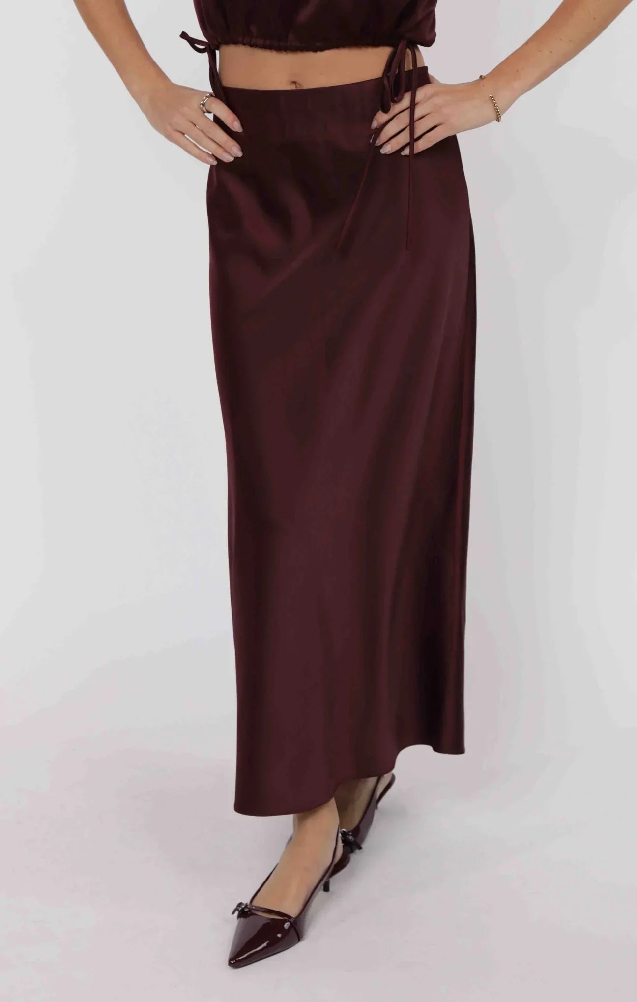 Model wearing wine satin bias cut midi skirt with sleek drape