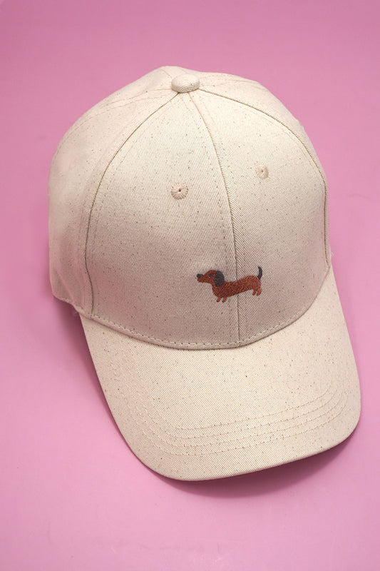 Beige cap with a small embroidered dachshund on a pink background