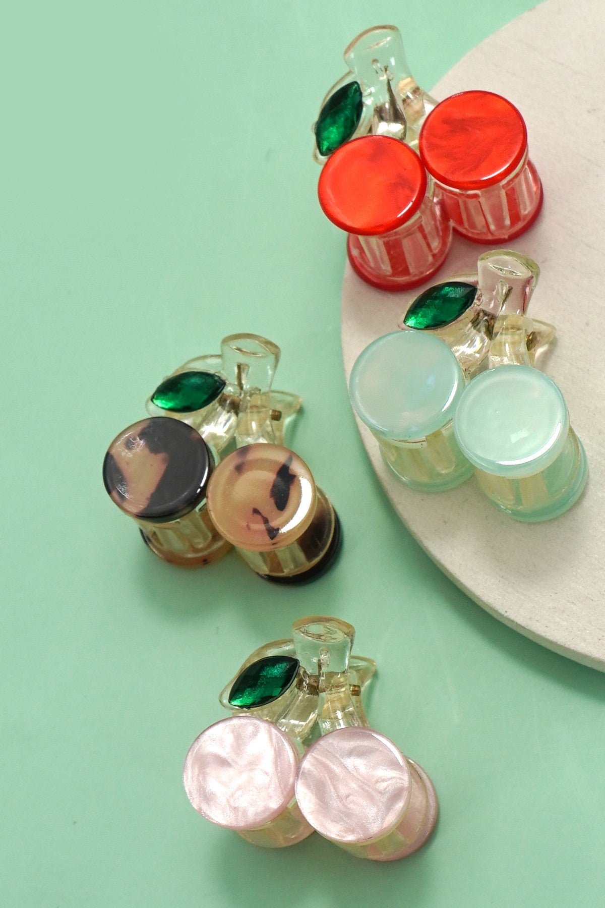 Set of four cherry-inspired mini hair claw clips with glossy finish and green leaf detail