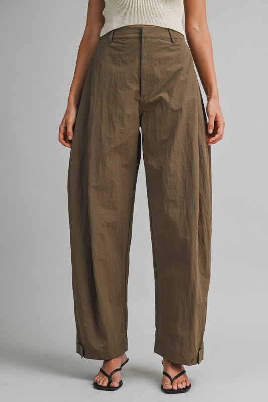 Model wearing high-waisted barrel pants with a structured curved silhouette and adjustable hem tabs