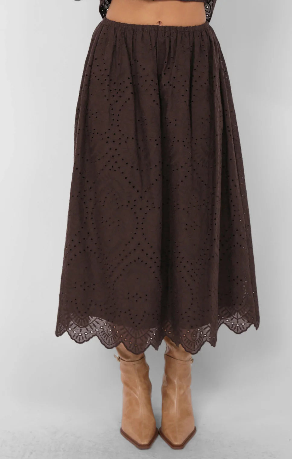 Model wearing brown eyelet midi skirt with scalloped hemline and boots