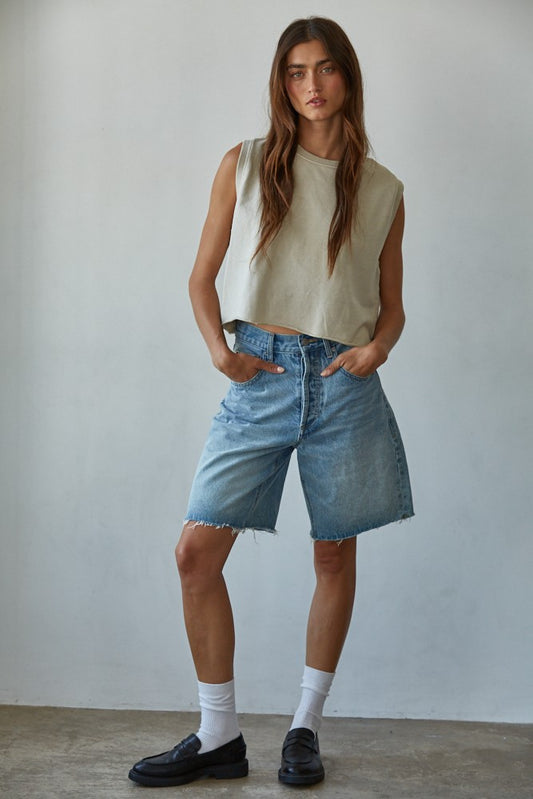 Woman wearing pigment-dyed beige sleeveless cotton tank with light wash denim bermuda shorts and black loafers