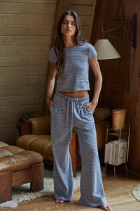 Woman wearing blue and white striped knit flare pants with drawstring waist and side pockets, styled with matching cropped striped top