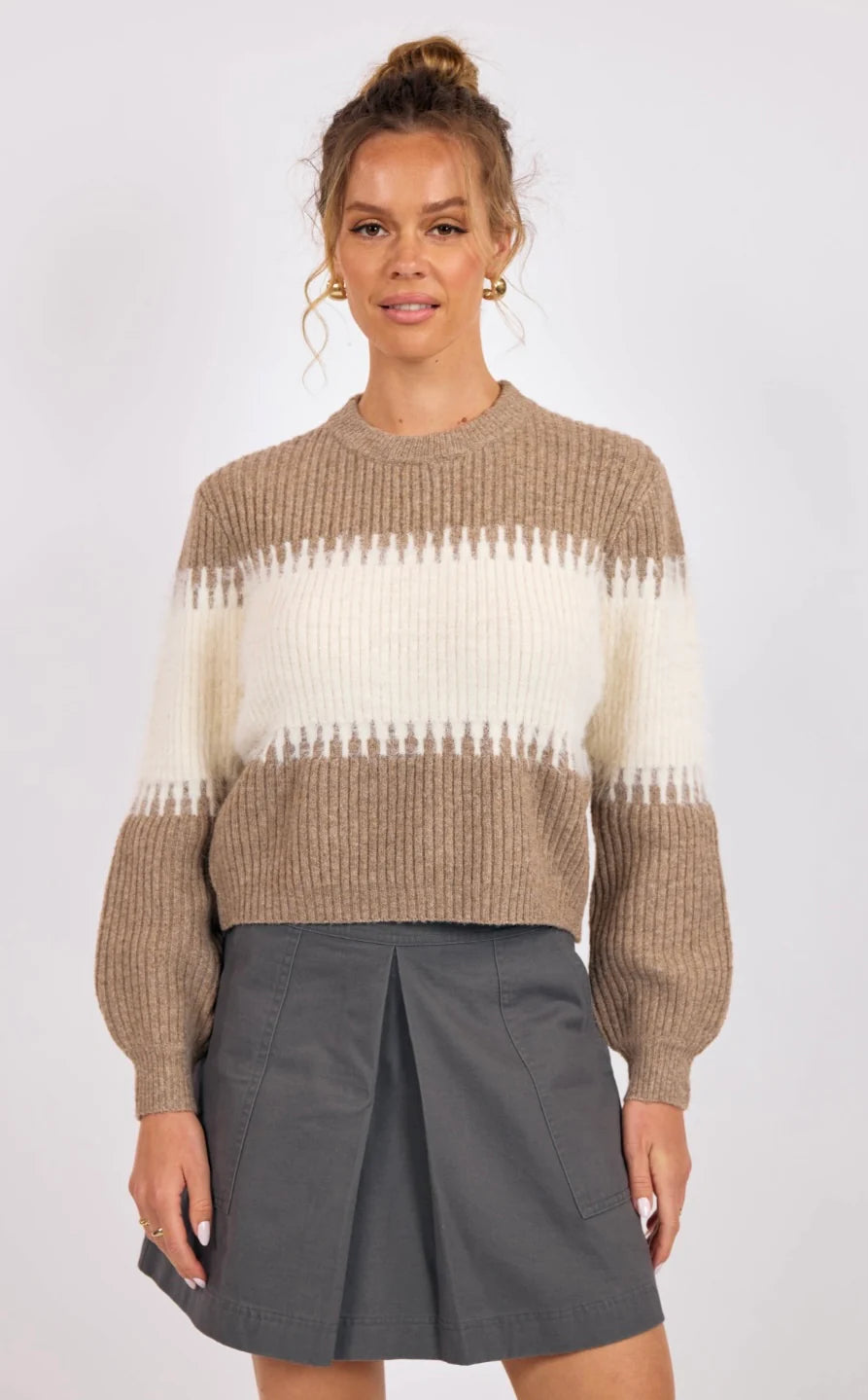 Woman wearing a striped sweater and gray skirt on a white background
