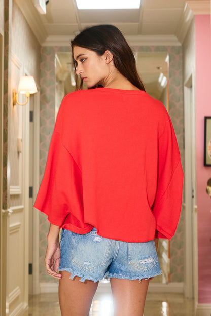 Woman wearing a red top and denim shorts in a hallway.