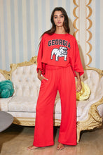Load image into Gallery viewer, Woman wearing a red &#39;Georgia&#39; sweatshirt and pants in an elegant room.