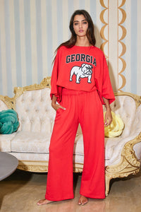 Woman wearing a red 'Georgia' sweatshirt and pants in an elegant room.