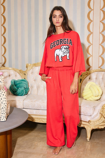 Woman wearing a red 'Georgia' sweatshirt and pants in an elegant room.