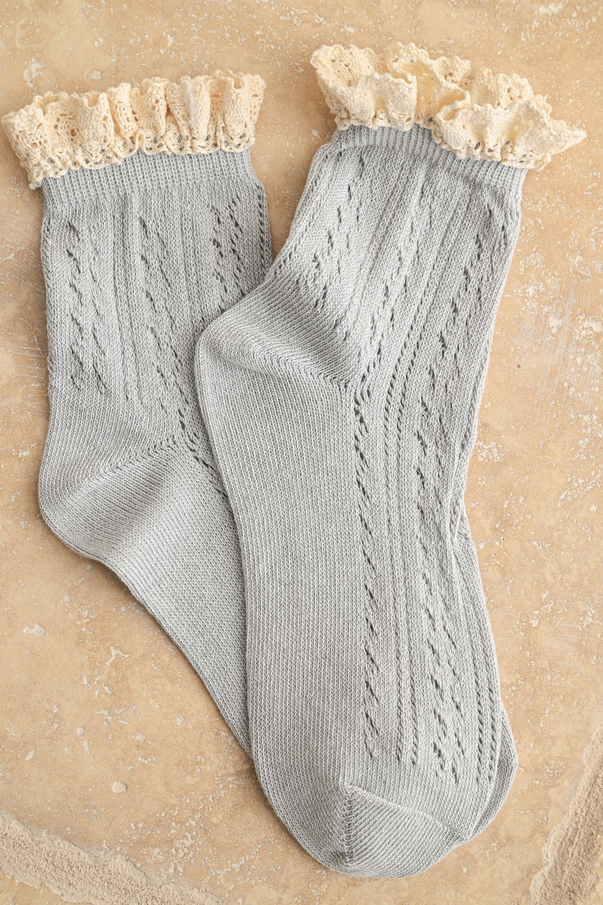 Pair of gray socks with lace top on a beige background