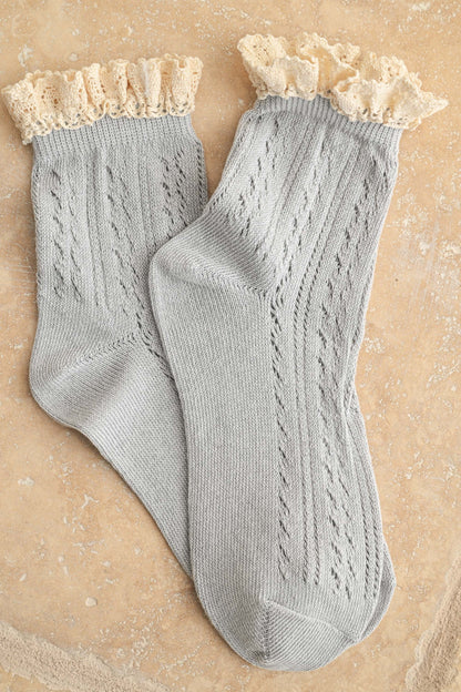 Pair of gray socks with lace top on a beige background