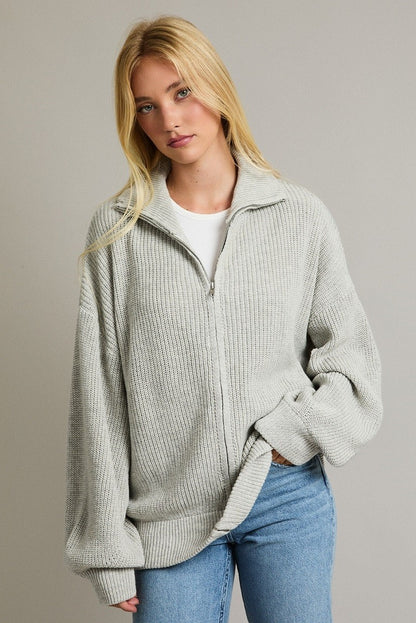 Woman wearing oversized zip-up cardigan sweater in light grey