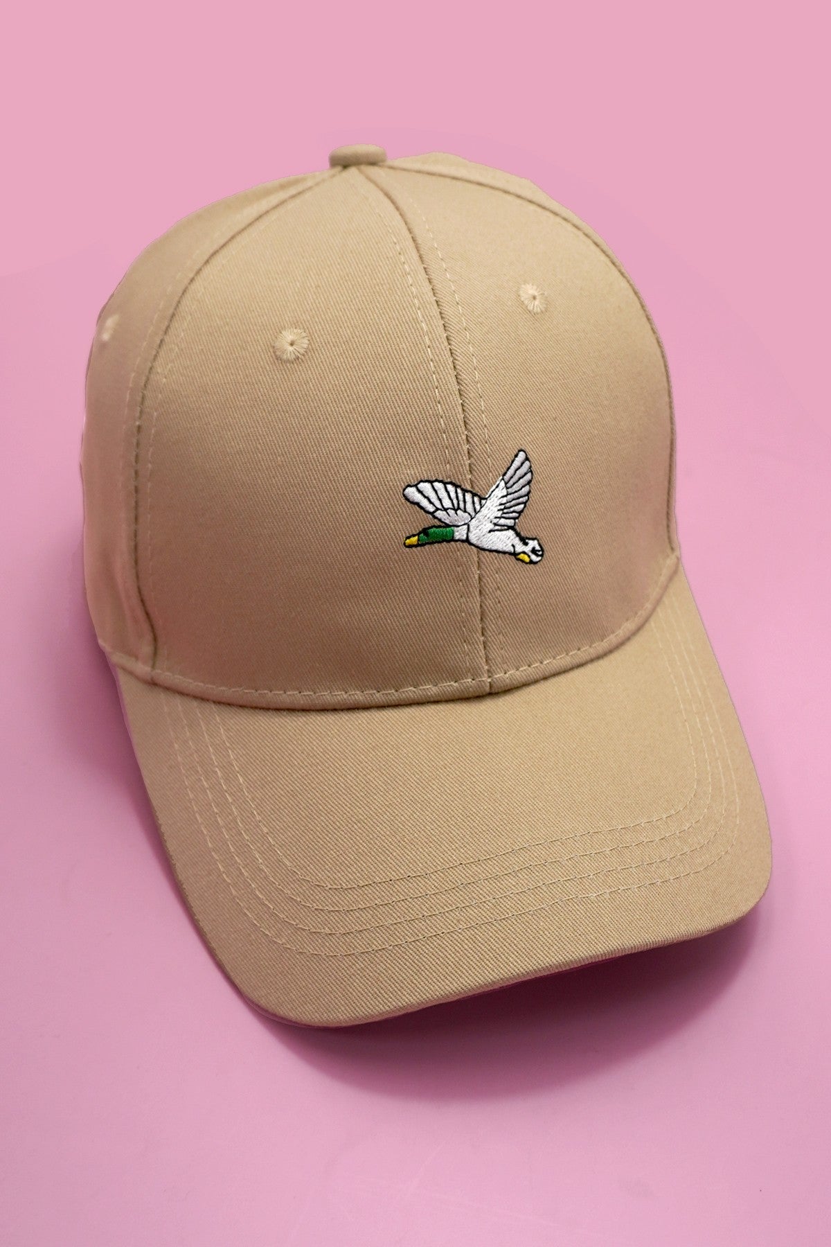 Beige cap with a duck logo on a pink background