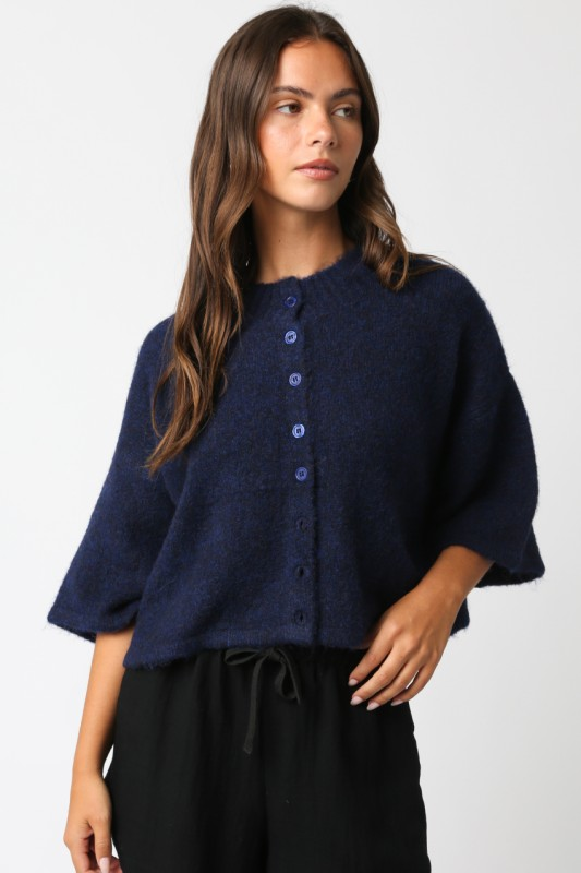 Woman wearing a navy blue cardigan over a black top on a white background