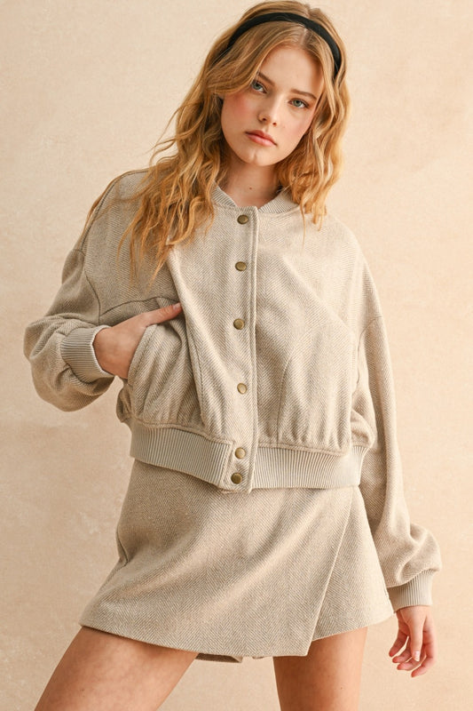 Woman wearing a beige jacket and skirt set against a beige background