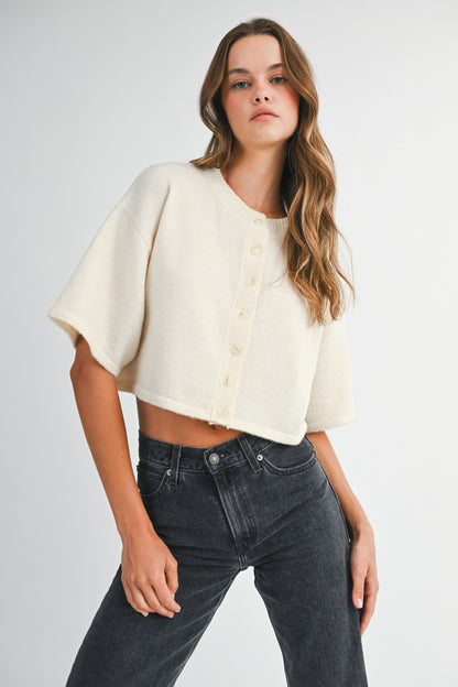 woman wearing cream cropped knit cardigan with elbow sleeves and black jeans
