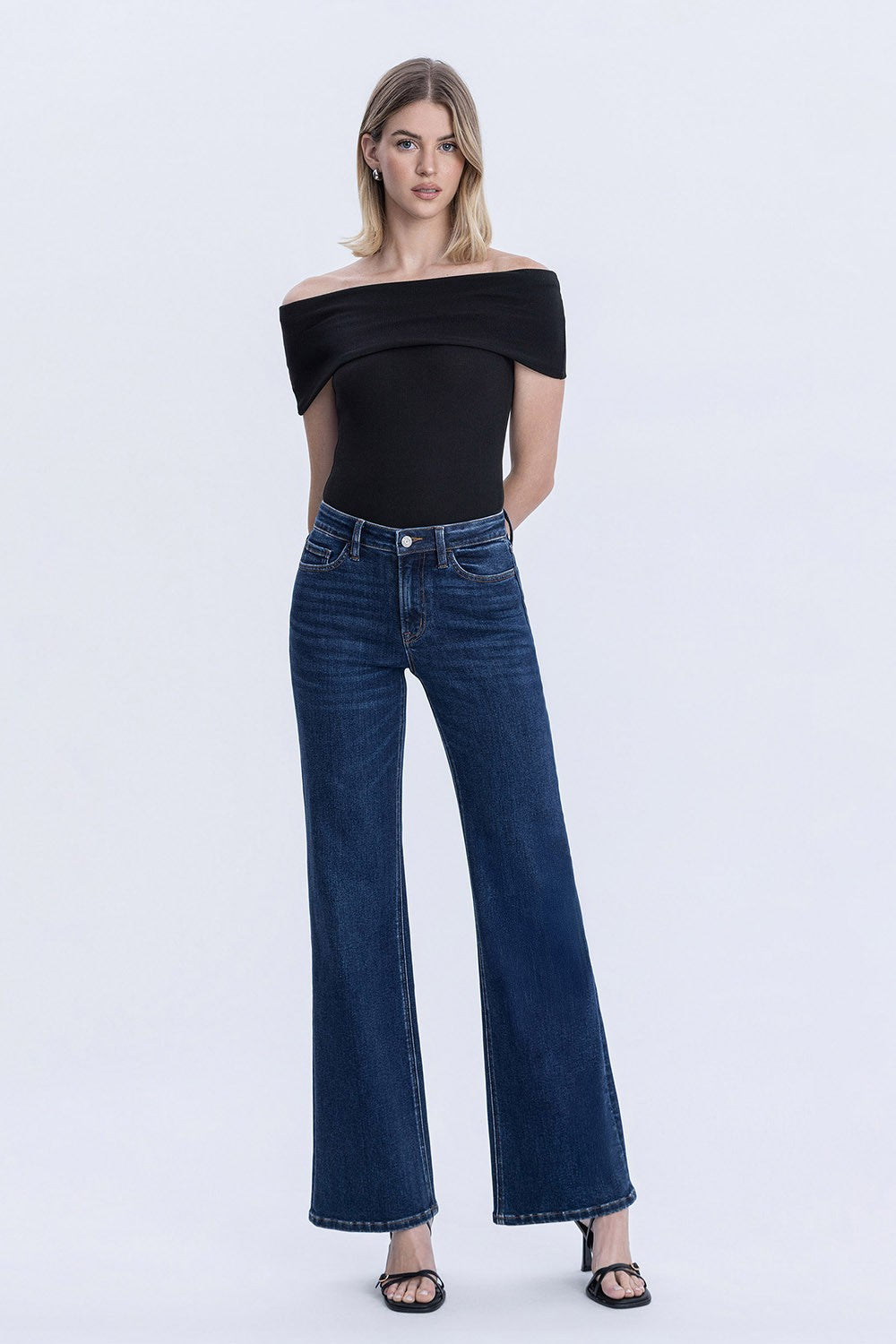 Woman wearing high rise dark wash vintage flare jeans with full length fit and finished hem