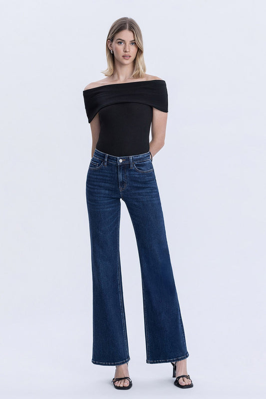 Woman wearing high rise dark wash vintage flare jeans with full length fit and finished hem