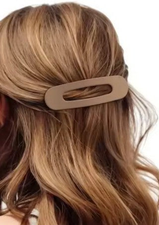 Beige hair clip in a person's hair with a neutral background