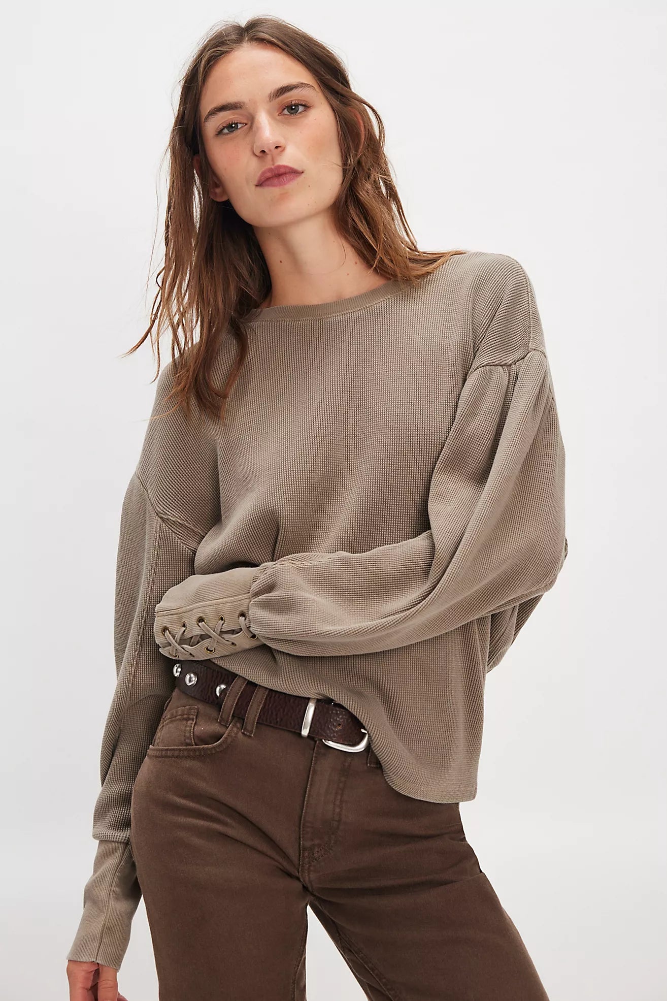 Model wearing oversized cotton waffle knit long sleeve top with lace-up cuff details in taupe.