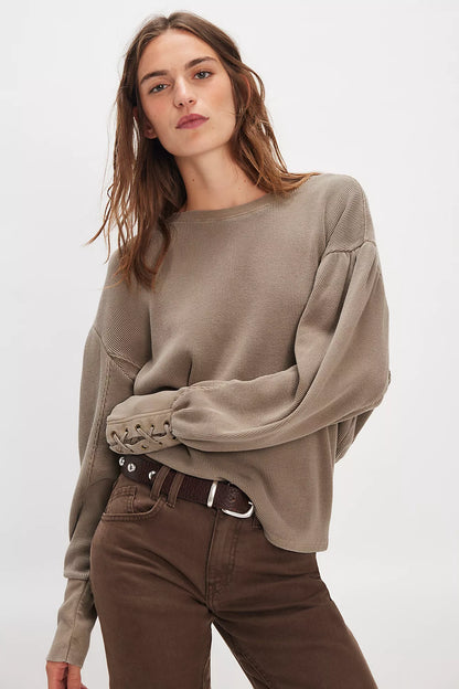 Model wearing oversized cotton waffle knit long sleeve top with lace-up cuff details in taupe.